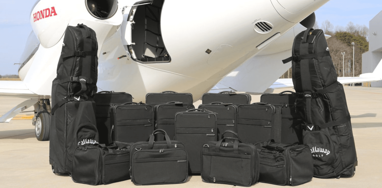 Suitcases, travel bags, and golf club bags displayed beside a HondaJet’s open aft baggage compartment